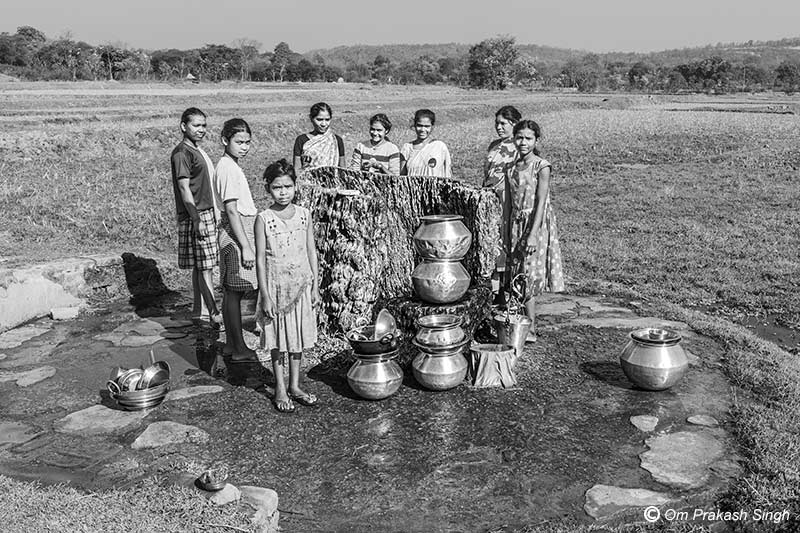 Munda women and young girls beside their traditional Kukuru Daarhi, a traditional spring-based drinking-water source used across generations in a tribal village in Jharkhand, India